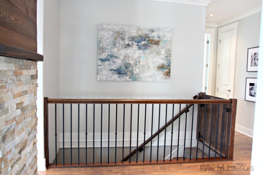Benjamin Moore Gray Owl in hallway and stairwell with dark stained wood railing and artwork on wall. Kylie M Interiors E-design and online color consulting