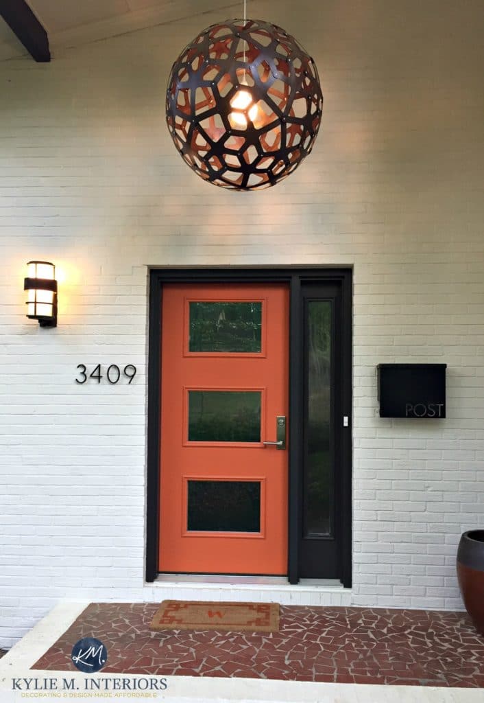 Exterior front door, mid century style painted orange with dark brown black trim and painted brick in a cream beige tone. Kylie M Interiors E-design and ONline Colour consulting decorating expert