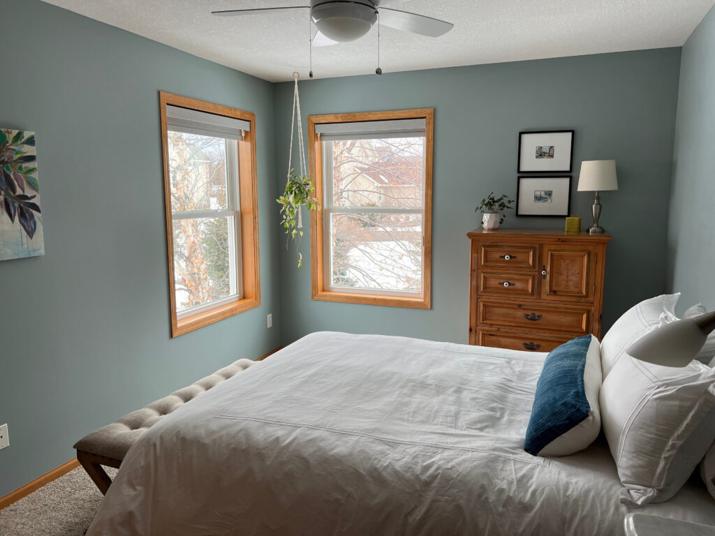 Guest bedroom in best blue green gray paint color, Benjamin Moore Mount Saint Anne, north facing, wood orange stain trim, beige carpet, Kylie M Interiors