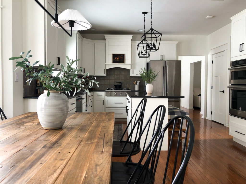 Kitchen with wood cabinets painted Warm white, Sherwin Williams Alabaster, black granite countertop, wood floor, dining area. Kylie M Interiors Edesign, Jenna Christians home