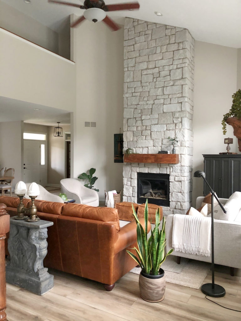 Living room vaulted tall stone fireplace, neutral greige taupe walls, Edgecomb. tobacco cognac leather sofa. Client photo, Kylie M Interiors Edesign