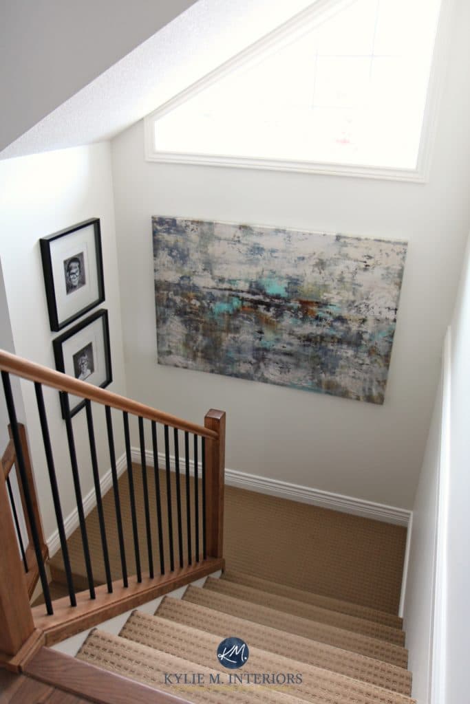 Stairwell with beige carpet, wood and metal railing and Sherwin Williams Creamy a light off-white paint colour. Kylie M Interiors E-design and colour consulting