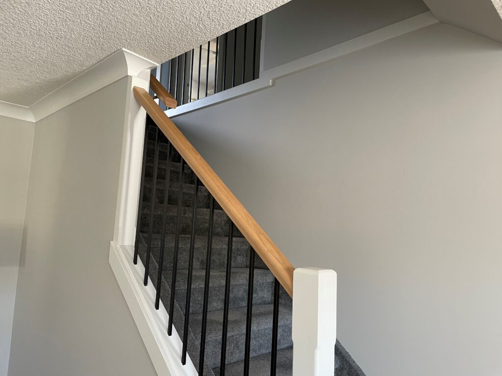 Benjamin Moore Light Pewter warm gray paint colour, staircase with gray carpet, wood handrailing, black metal spindles. Kylie M Edesign