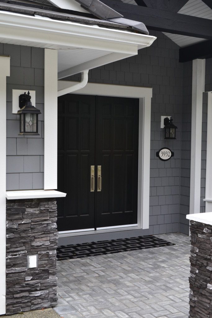 Black front door with dark gray siding and white trim on the exterior of a new home