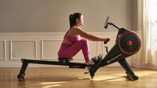 Echelon Row review: A woman in pink workout gear uses the rower in her living room