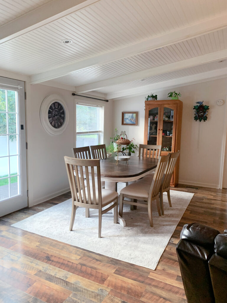 Sherwin Williams White Duck dining room sloped vaulted ceiling white with shiplap and painted beams, wood floor. Kylie M